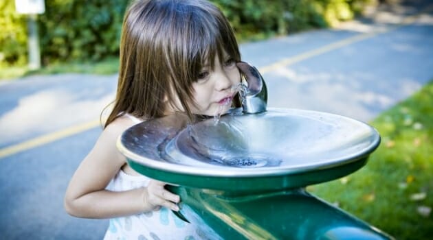 Girl drinks from drinking fountain