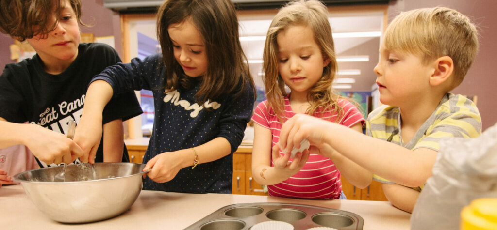 Four kids in Kids On The Go helping make muffins for snack time