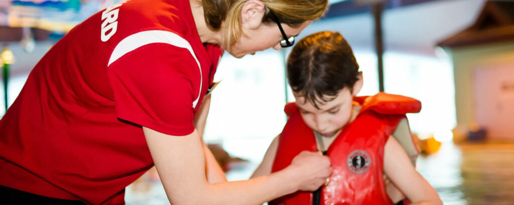 Lifeguard helping boy put on lifejacket