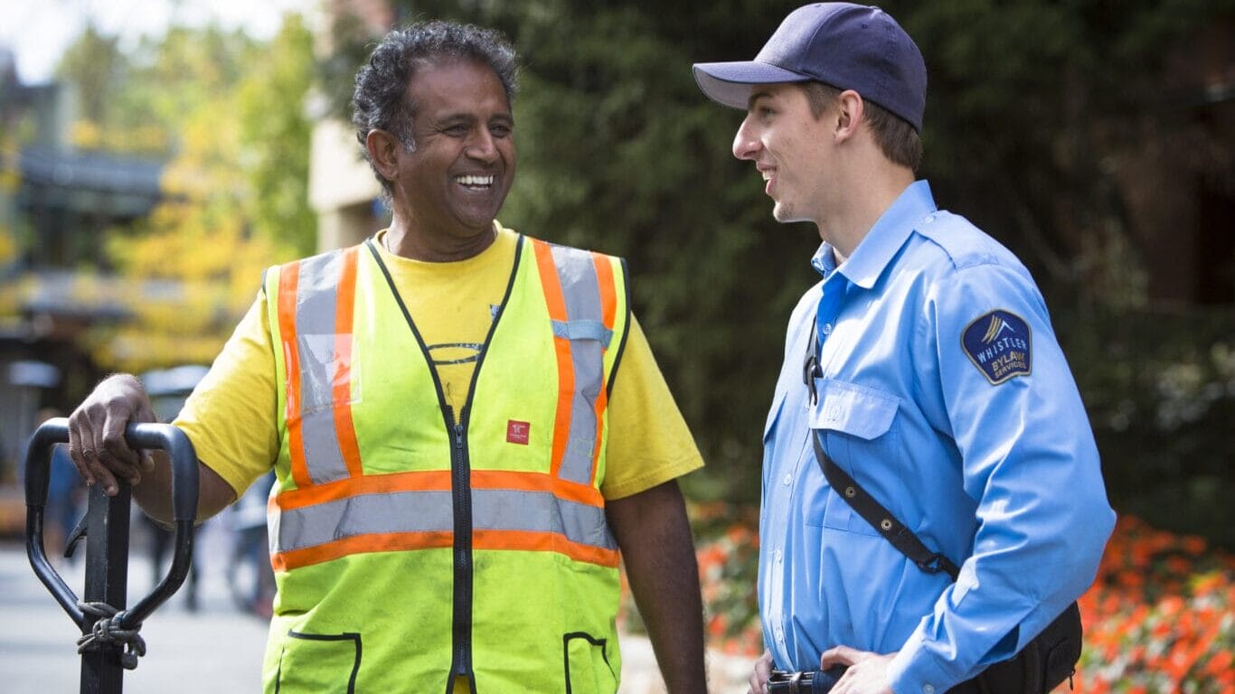Whistler bylaw officers smiling on the Village Stroll on a sunny day
