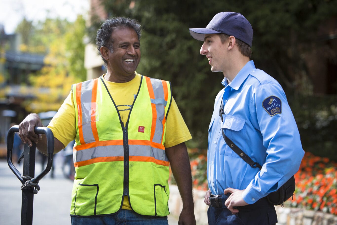 Whistler bylaw officers smiling on the Village Stroll on a sunny day