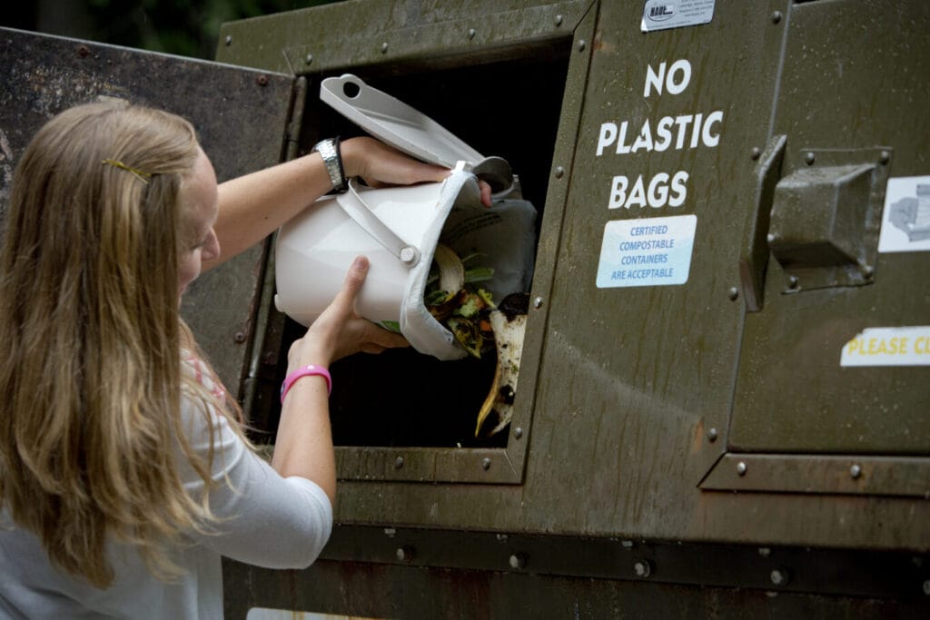 Woman dumping food scraps into compost bin.