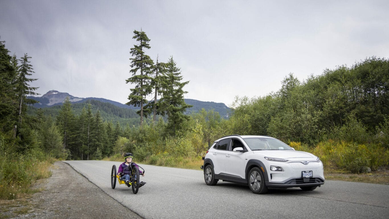 Biker on an adaptive bike and car travel near Spruce Grove