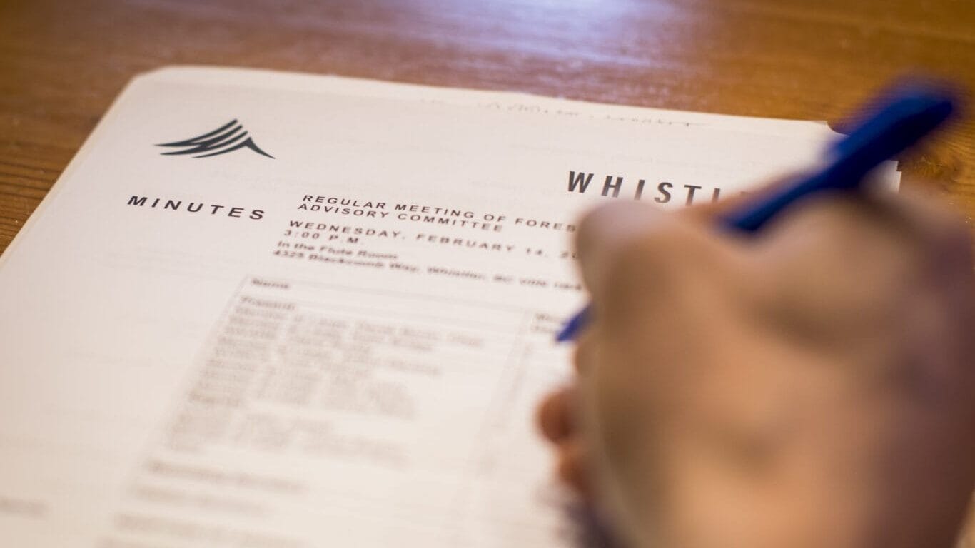 A person writes on an agenda during a Council meeting