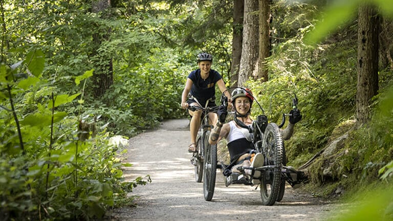 An adaptive biker and mountain biker share the trail in Whistler
