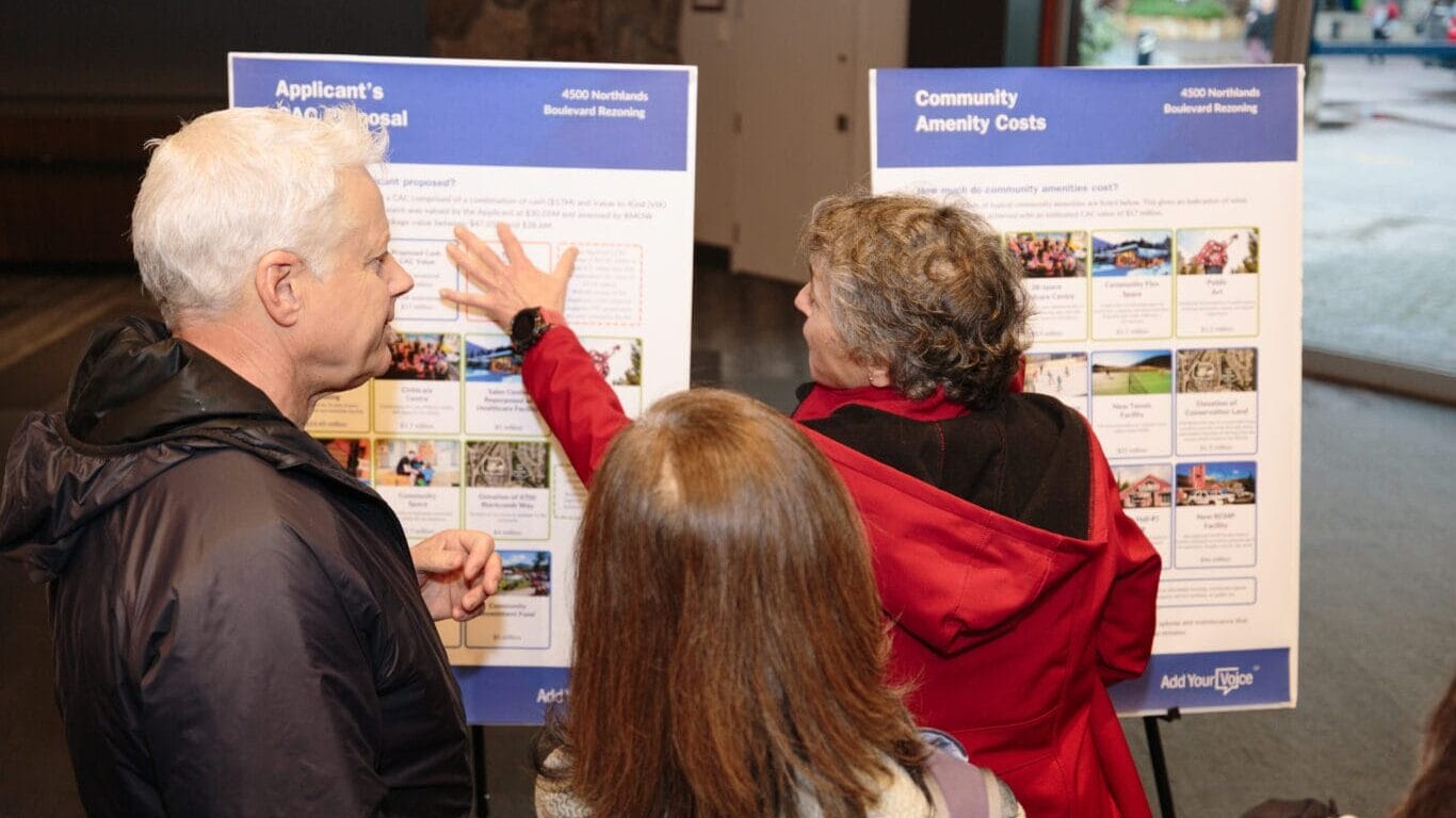 Community members discuss information boards at the Add Your Voice event