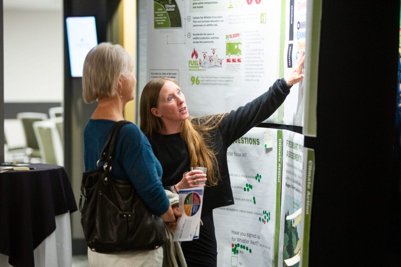 Staff person show a member of the public a display board